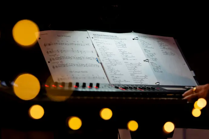 a keyboard with sheet music on it in a dark room